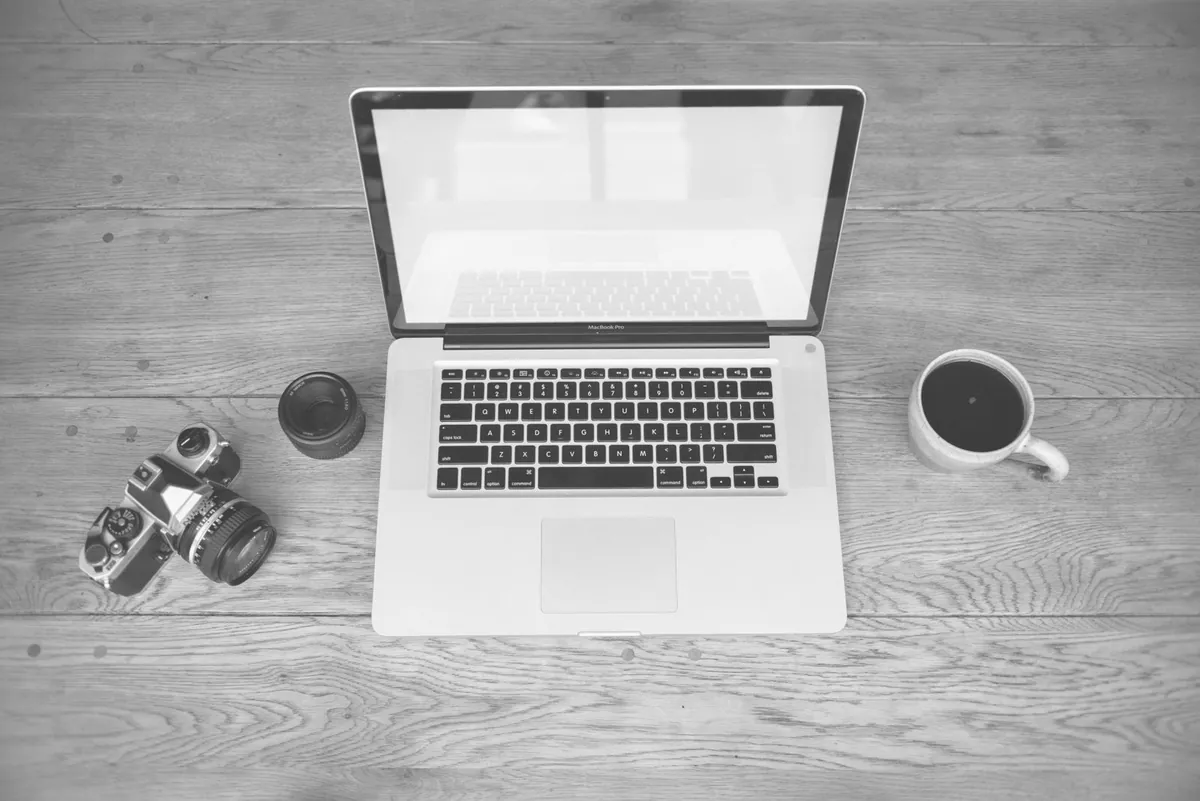 photographer at desk with laptop and camera